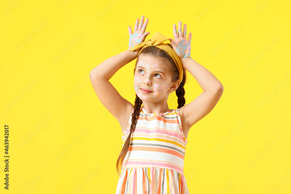 Funny little girl in paint on yellow background