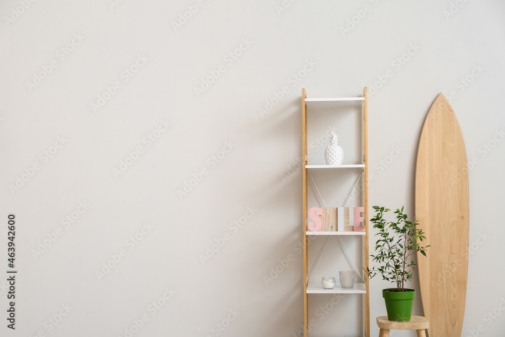 Stylish shelf unit with decor and houseplant near light wall, closeup