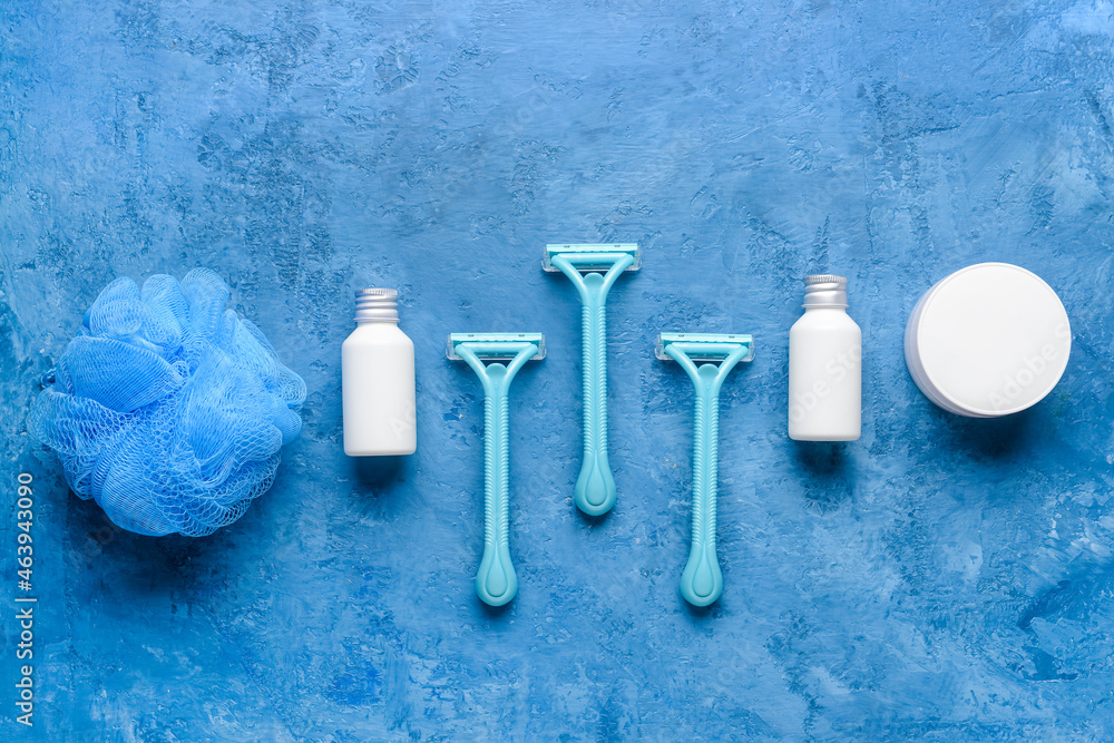 Safety razors, sponge and cosmetic products on blue background