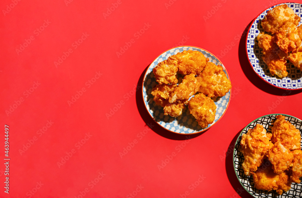 Plates with popcorn chicken on color background