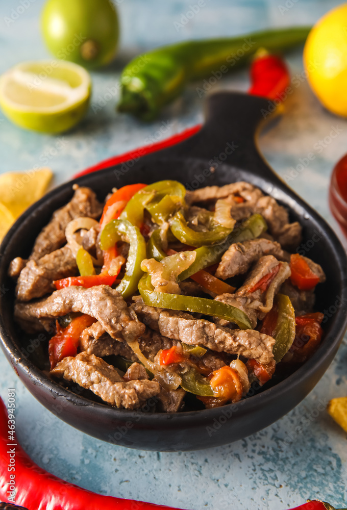 Frying pan with tasty Fajita on color background, closeup