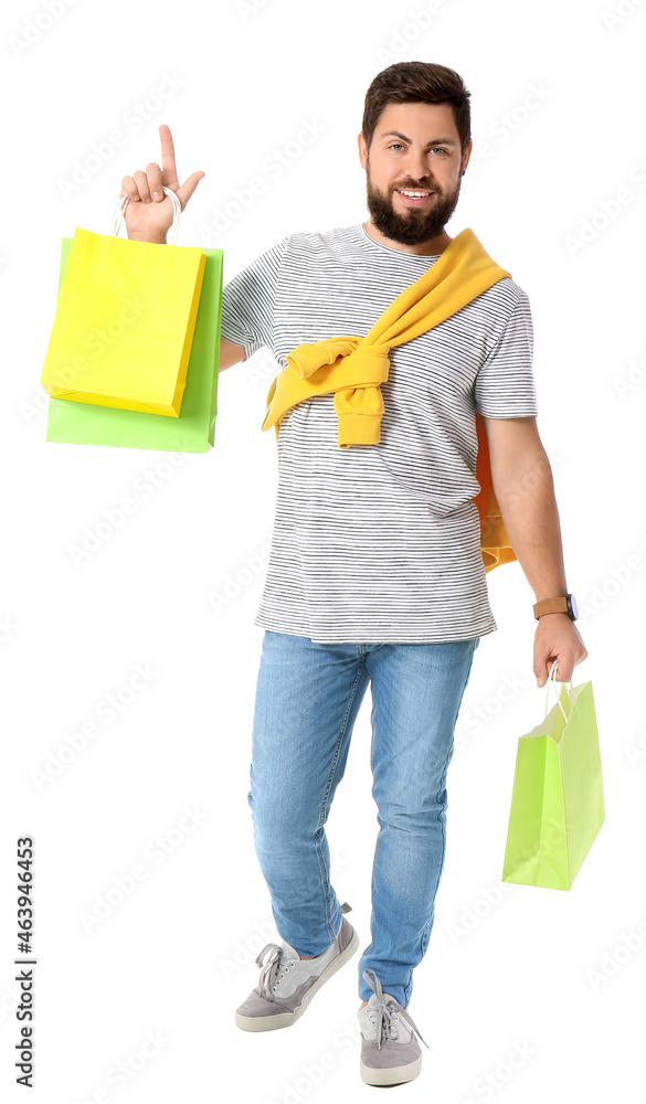 Handsome man with Black Friday shopping bags pointing at something on white background