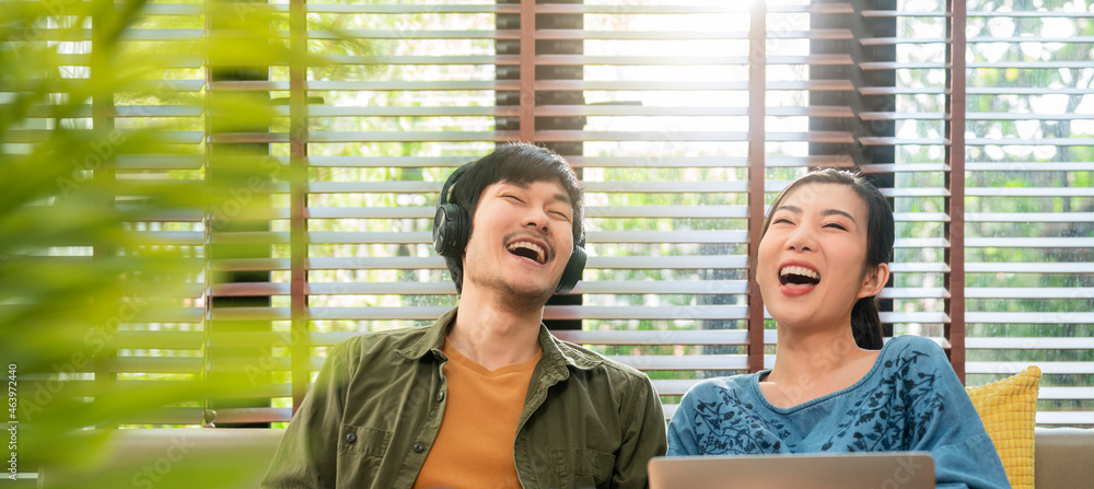 portrait shot of asian lovely husband and wife wear casual cloth sitting on sofa listen music headph