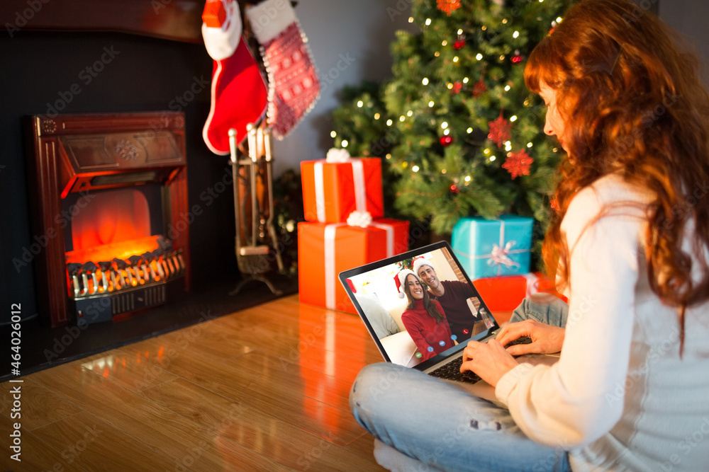 Caucasian woman on christmas laptop video call with smiling couple