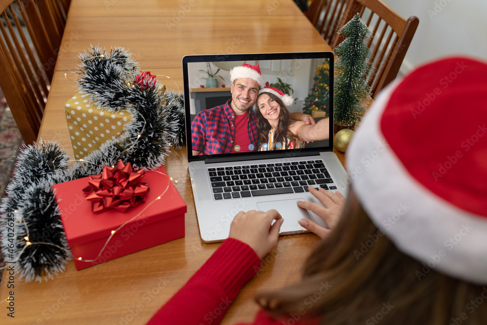 Caucasian woman making laptop christmas video call with smiling caucasian couple