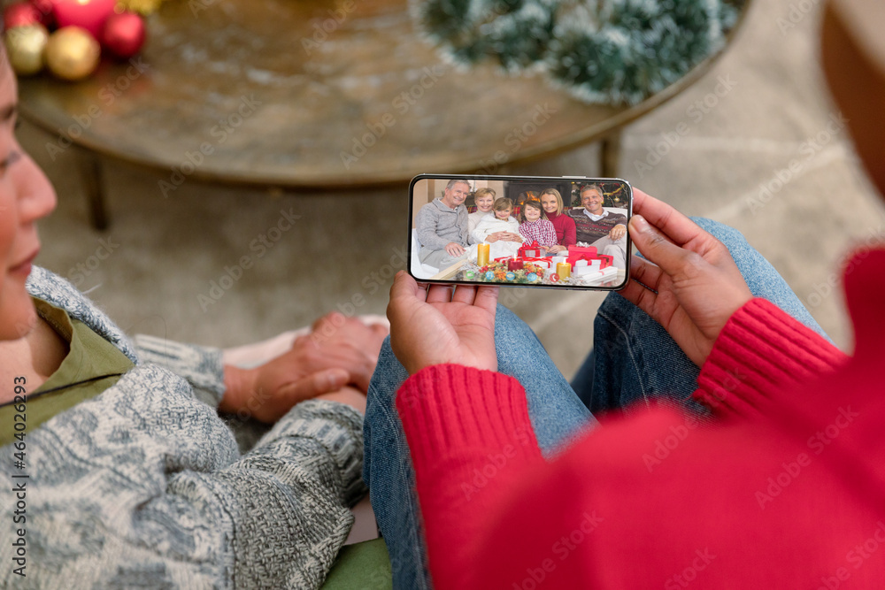 Smiling diverse friends making smartphone christmas video call with multi generation family