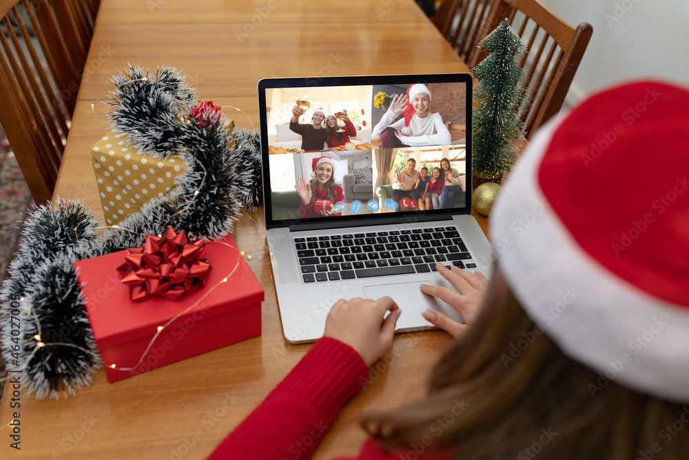 Caucasian woman on christmas laptop video call with diverse group of friends