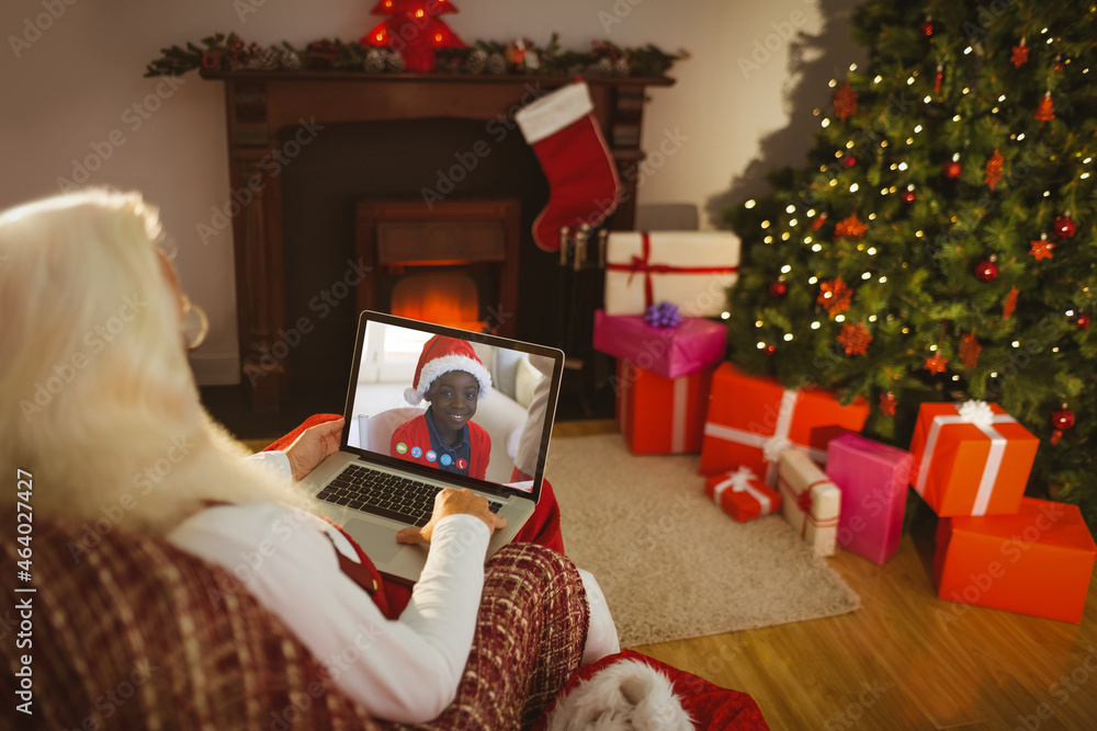 Caucasian santa claus on christmas laptop video call with african american boy