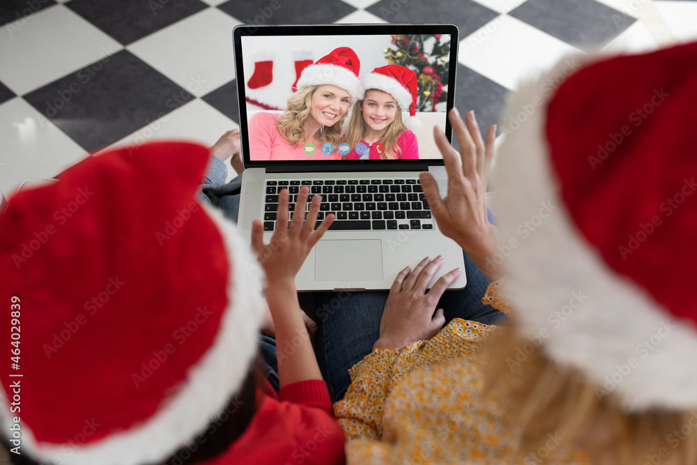 Caucasian mother and child in santa hats on christmas video call on laptop with friends