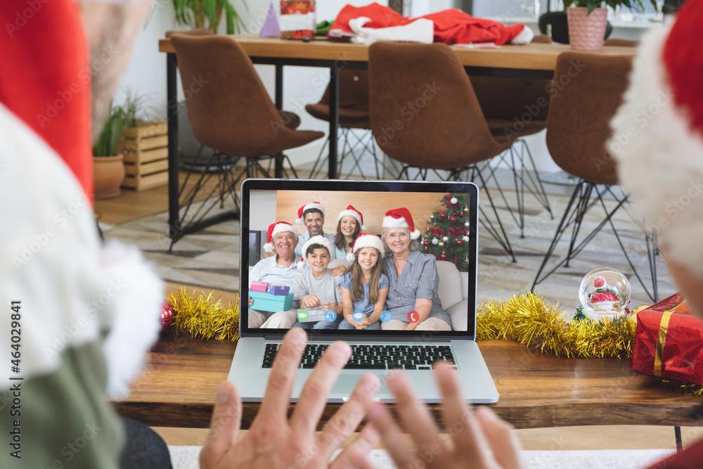 Caucasian couple in santa hat on christmas video call on laptop with family