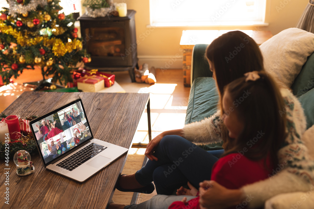 Caucasian mother and daughter on christmas video call on laptop with friends and family