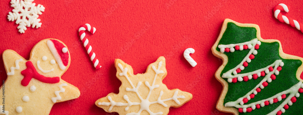 Decorated Christmas gingerbread cookies on red table background.