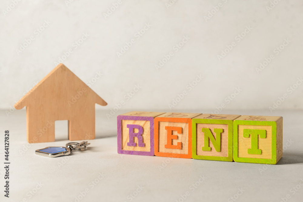 Wooden house with word RENT and key on white background