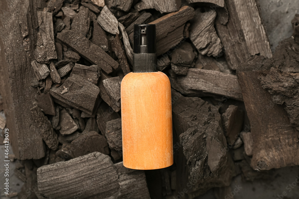 Wooden cosmetic bottle on charcoal background