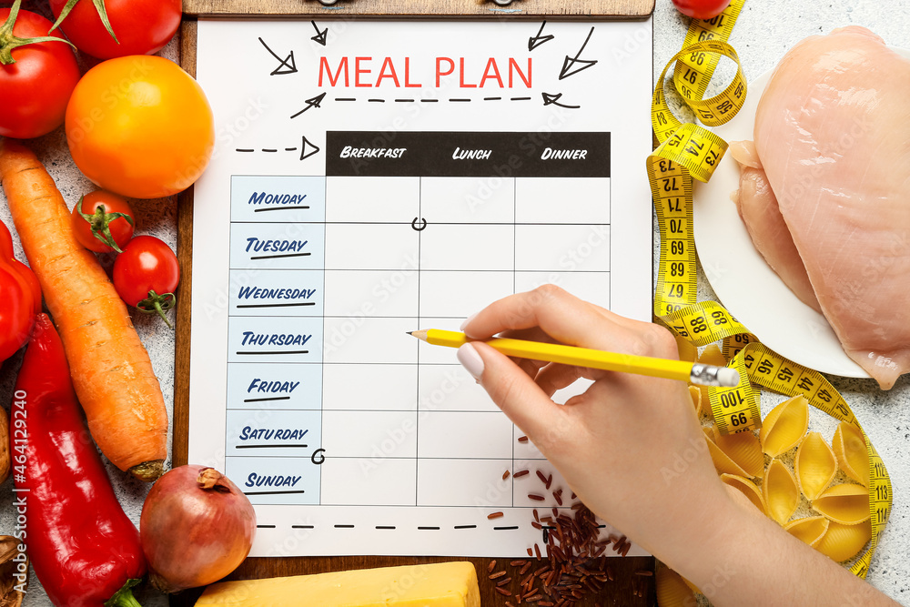 Woman making meal plan on light background