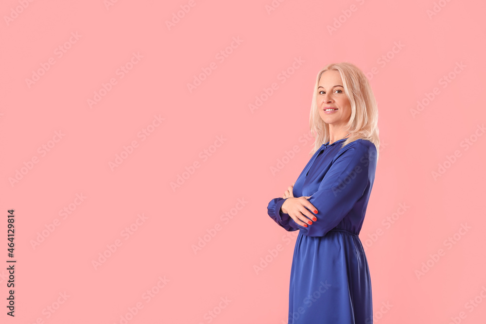 Beautiful mature woman in blue dress on pink background