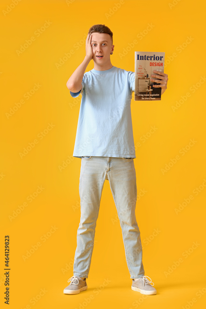 Surprised young man with magazine on yellow background