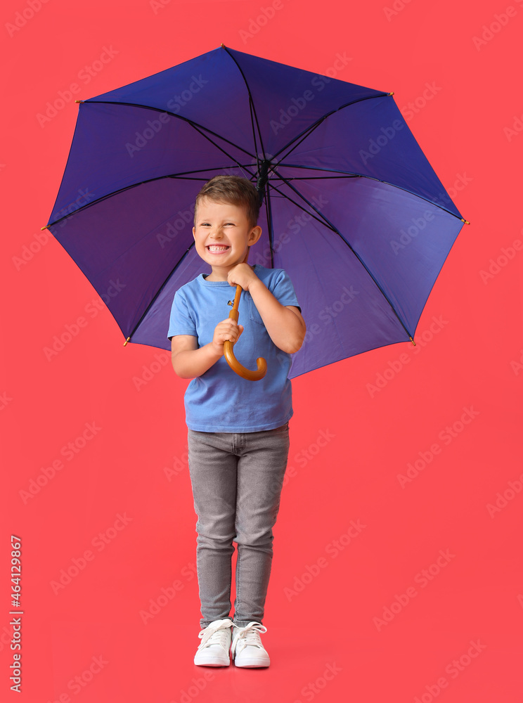 可爱的小男孩，红色背景下有一把蓝色雨伞