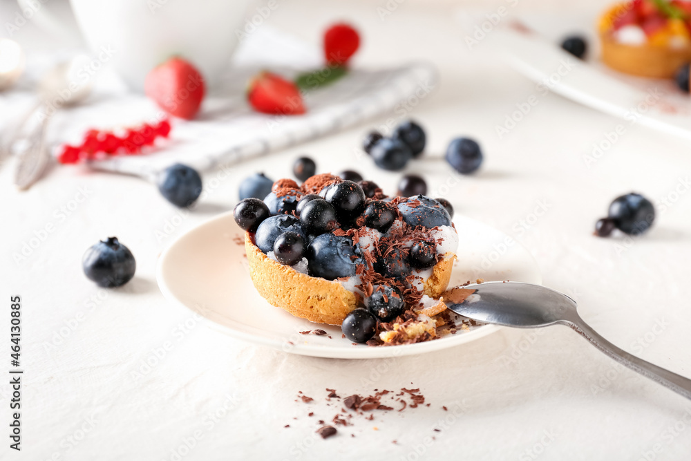 Plate with tasty berry tart on light background