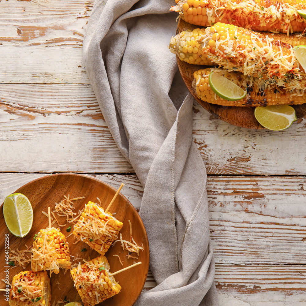 Plates with pieces of delicious Elote Mexican Street Corn on white wooden background