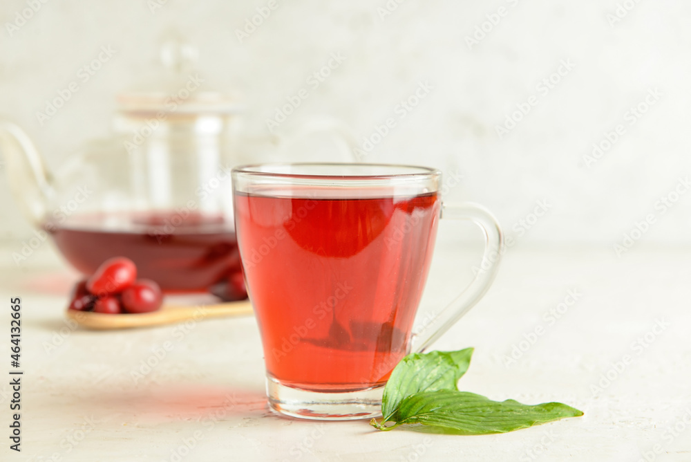 Cup of healthy dogwood berry drink on light background