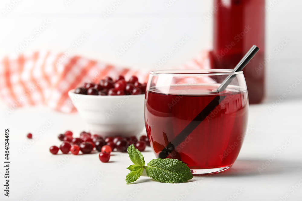 Glass with healthy cranberry juice on light background