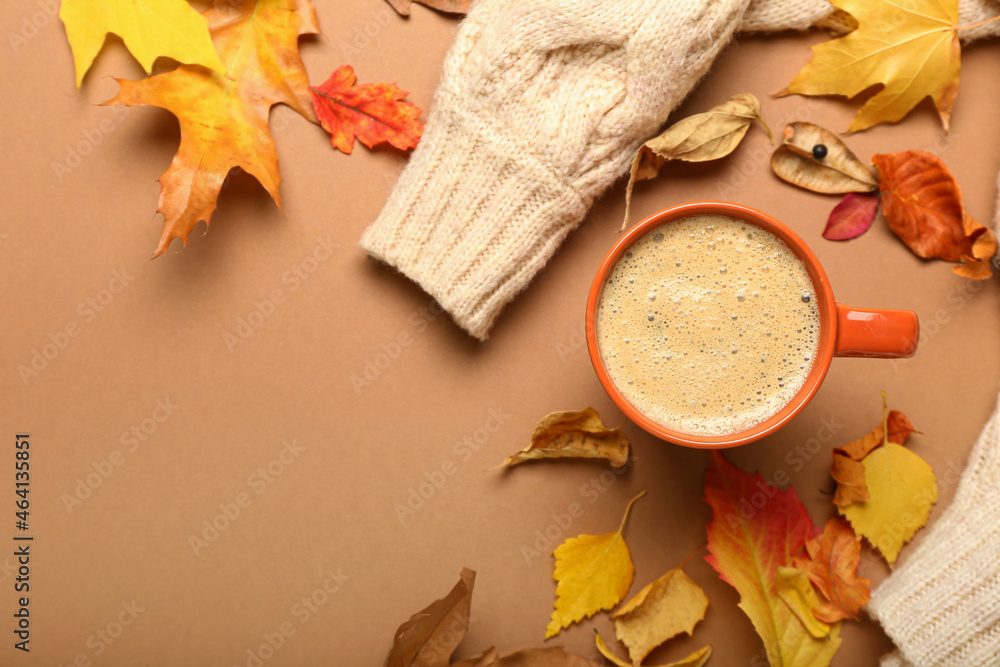 Composition with cup of coffee, sweater and autumn leaves on brown background