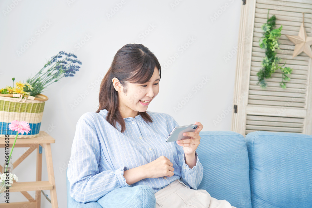 部屋でスマホを使う女性