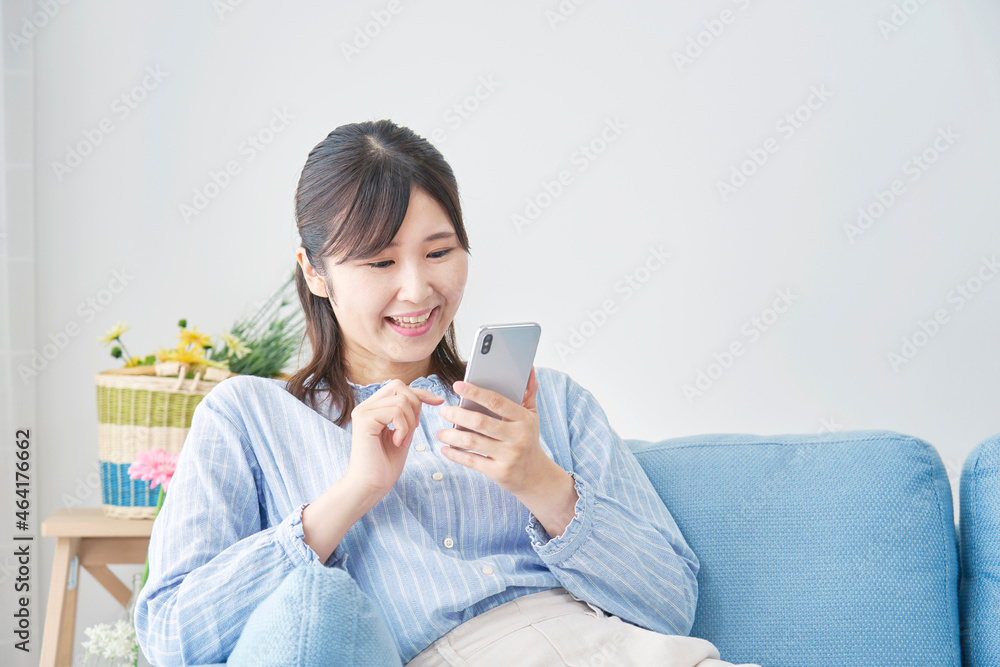 部屋でスマホを使う女性