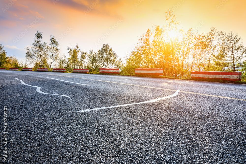 Empty asphalt road and autumn trees landscape at sunset.