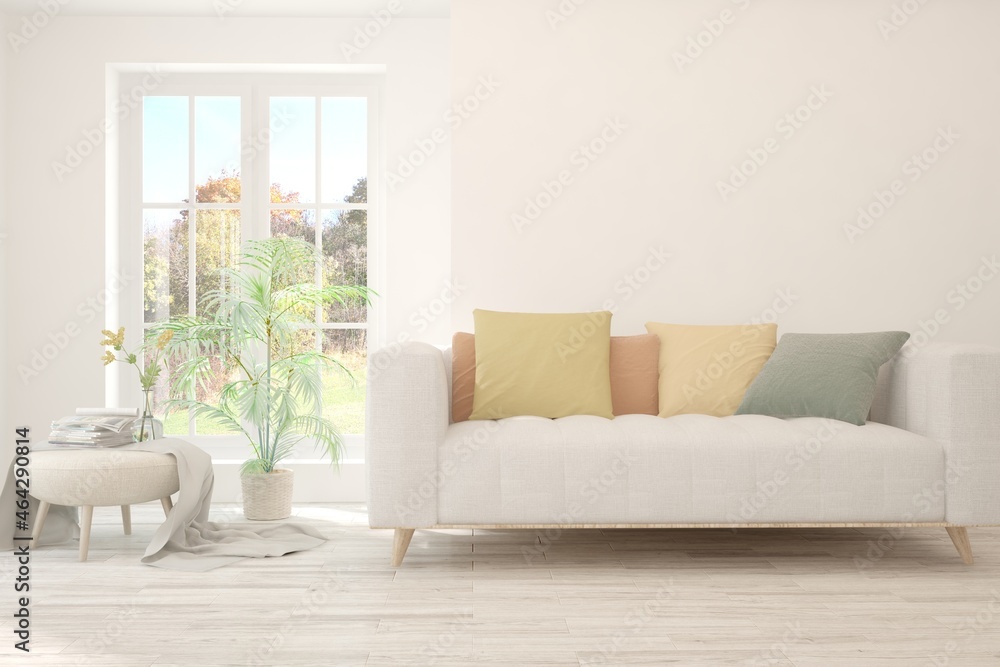 Stylish room in white color with sofa and autumn landscape in window. Scandinavian interior design. 