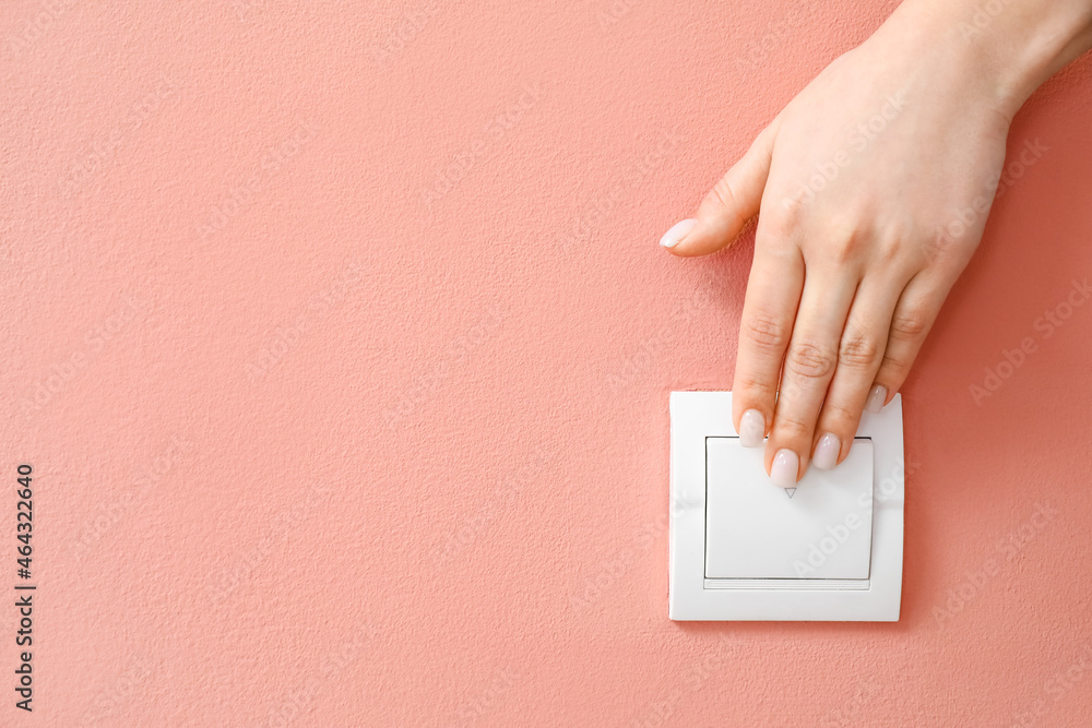 Woman switching on light near pink wall, closeup