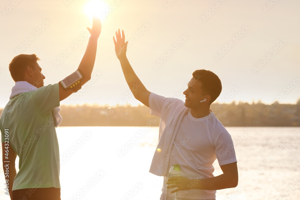 Sporty young men giving each other high-five after training outdoors