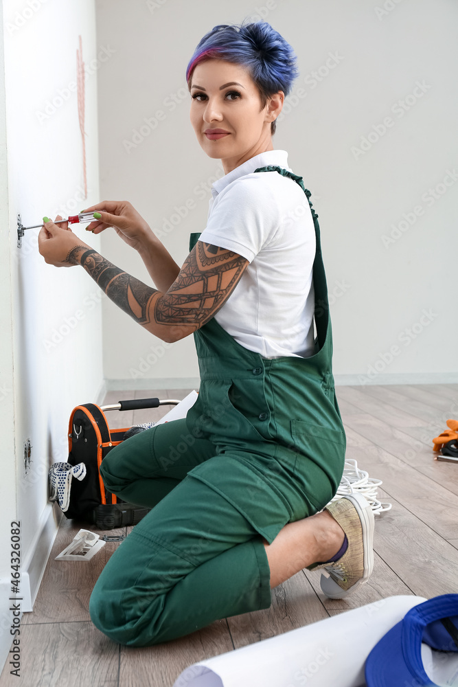 Female electrician repairing socket in room