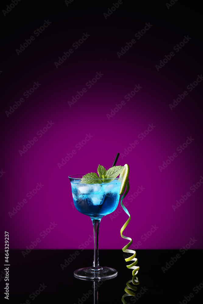 Glass of Blue Lagoon cocktail on dark color background