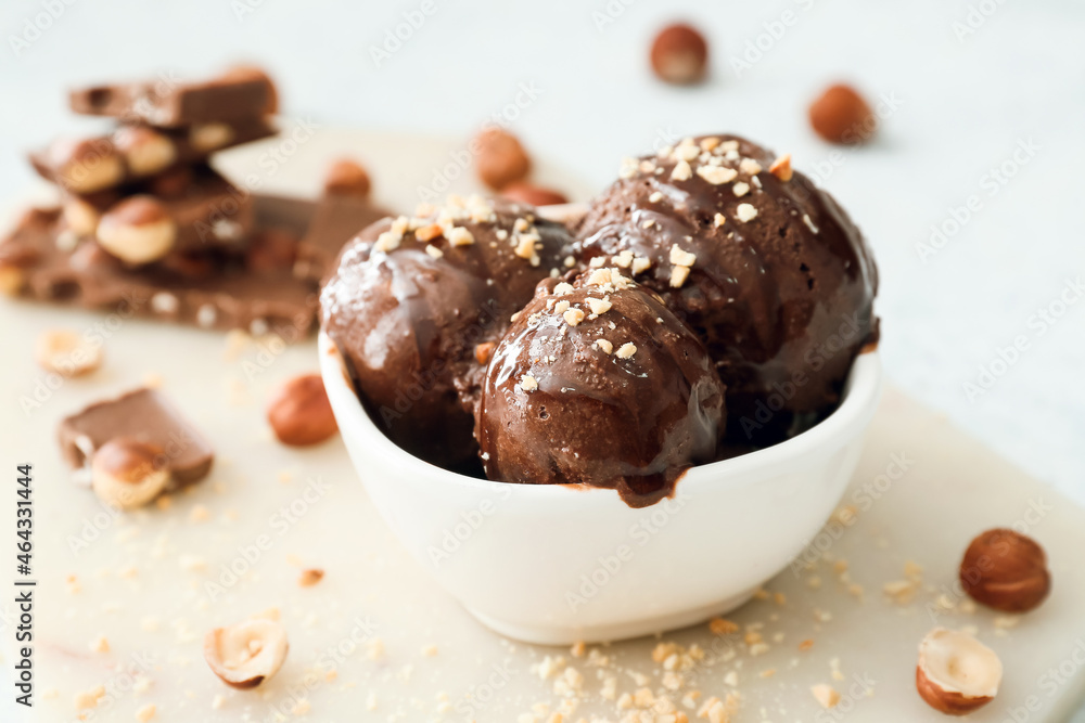 Bowl of tasty chocolate ice cream with nuts on white background