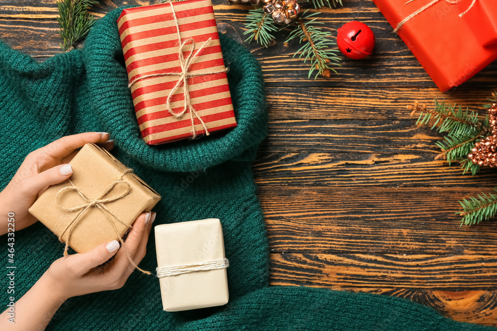 Female hands with different Christmas gifts on wooden background, closeup