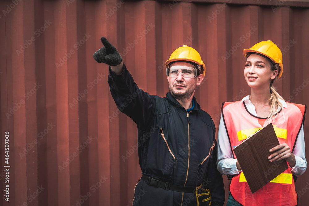 Industrial worker works with co-worker at overseas shipping container yard . Logistics supply chain 