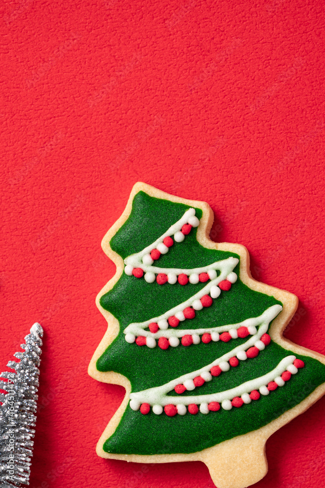 Decorated Christmas gingerbread cookies with decorations on red table background.