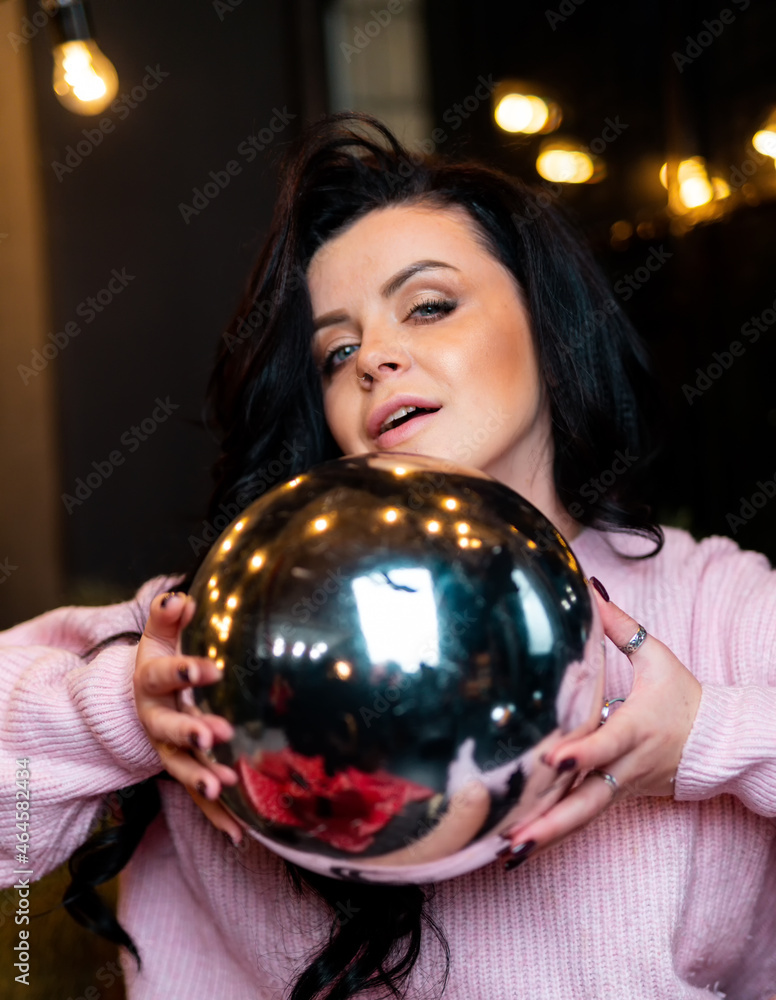 Beautiful attractive female with christmas ball. Pretty woman in sweater posing with christmas ball.