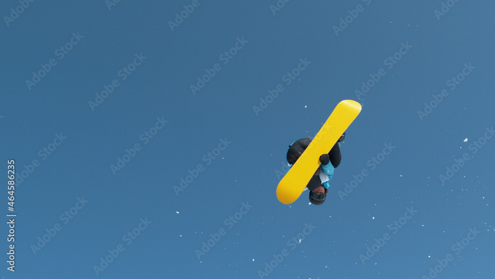 Male tourist snowboarding in Alps jumps into air and performs a grab trick.