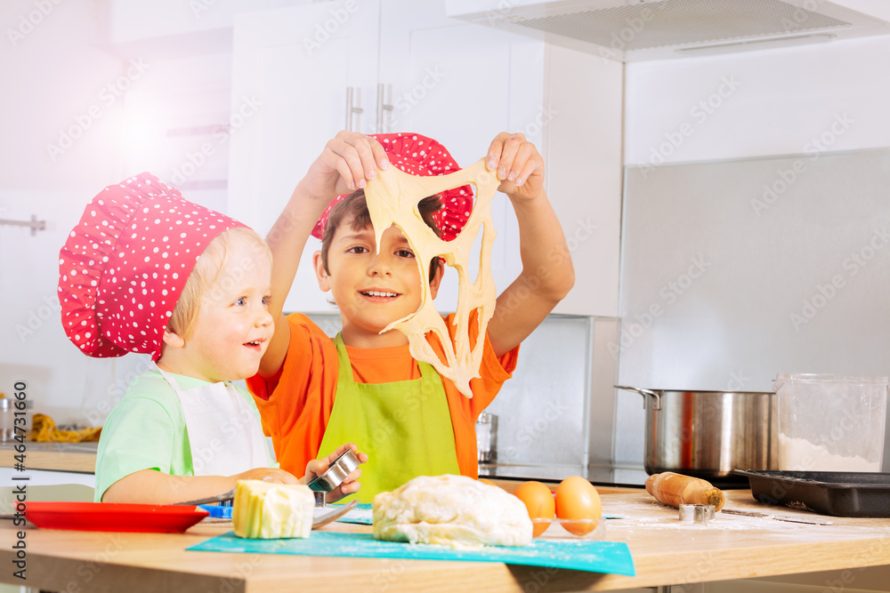 Smiling boy play holding dough cutting out cookies