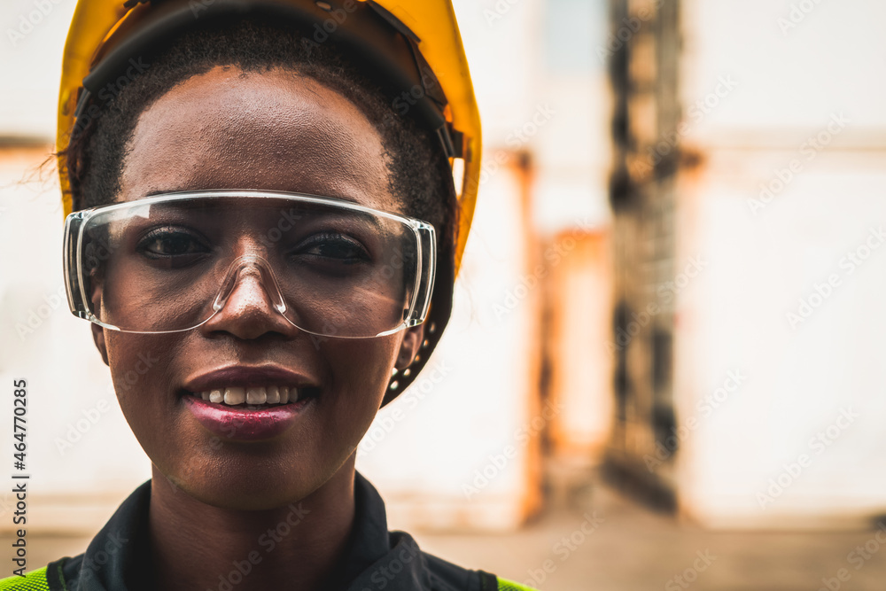 Young African American woman worker at overseas shipping container yard . Logistics supply chain man