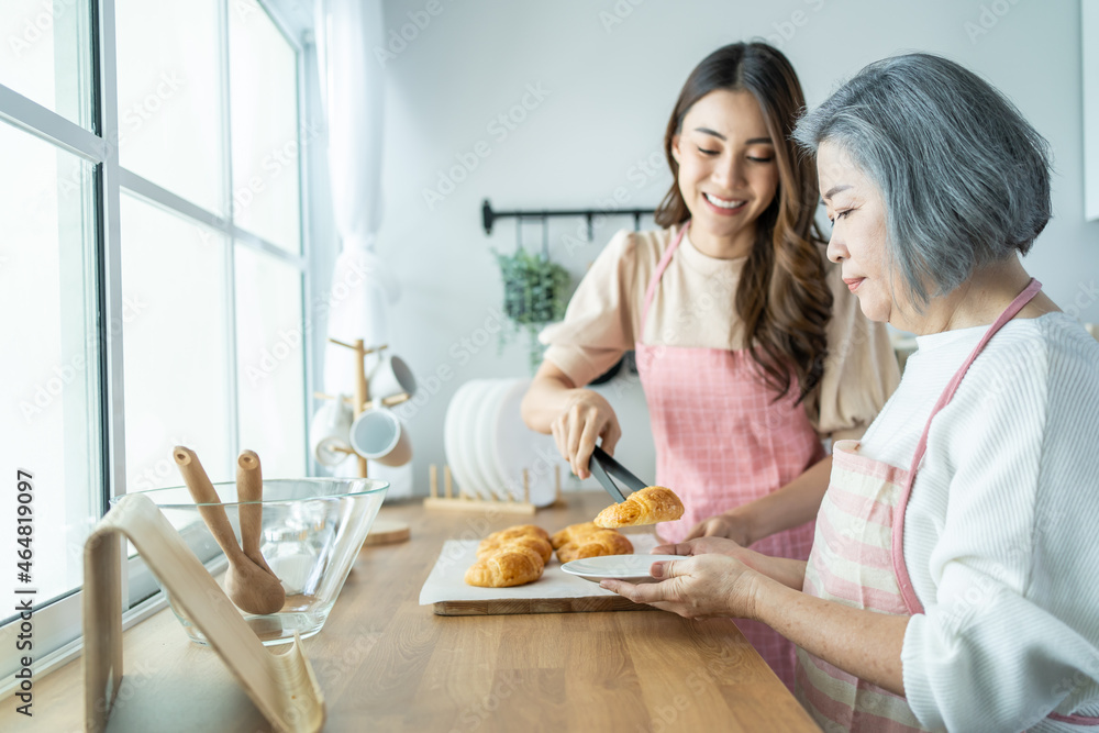 亚洲可爱的家庭，年轻的女儿在厨房里看着老母亲做饭。