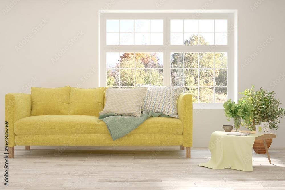 Stylish room in white color with sofa and autumn landscape in window. Scandinavian interior design. 