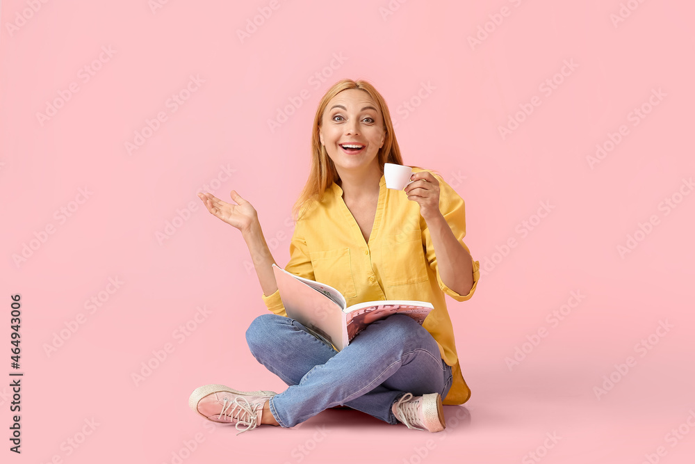 Surprised mature woman with cup of coffee and magazine on color background