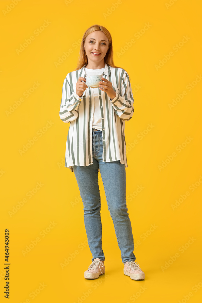 Beautiful mature woman with cup of coffee on color background