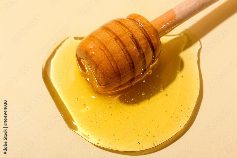 Wooden dipper with sweet honey on color background, closeup