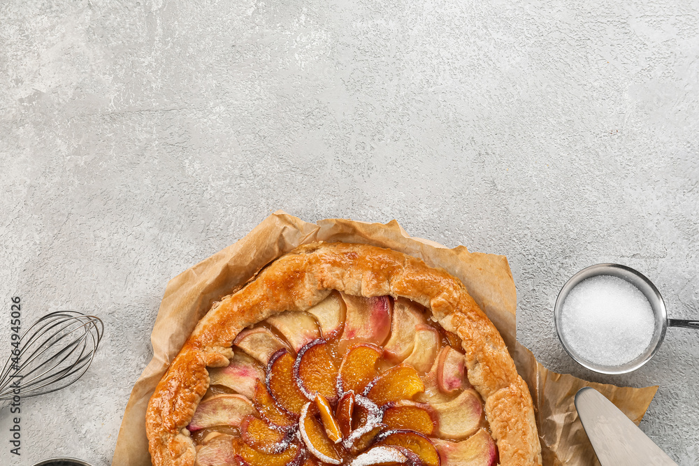 Parchment with tasty peach galette on light background