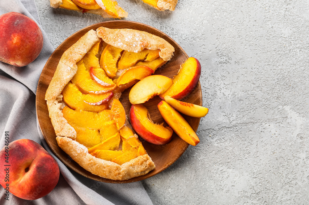 Plate with tasty peach galette on light background